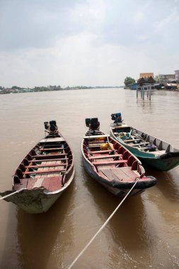Nehirdeki suya inen üç tahta tekne makinesi. Bir motor tarafından suya itilen küçük bir gemi..