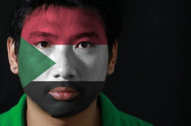 Yüzünde Sudan bayrağı olan bir adamın portresi siyah zemin üzerine çizilmiş, kırmızı beyaz ve siyah; kaldırma tabanlı yeşil üçgen.