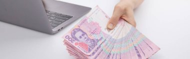 Dizüstü bilgisayarda çalışan ve elinde hryvnias tutan kadın, yakın görüş