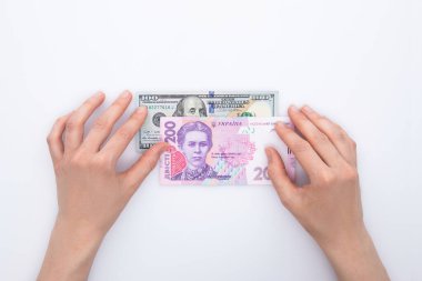 Beyaz arka planda izole edilmiş Hryvnia ve dolar banknotları tutan kadın elleri, yakın görüş