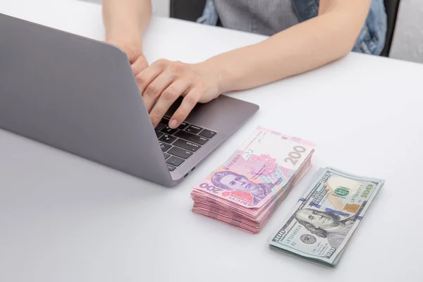 Hryvnia yakınlarında dizüstü bilgisayarda çalışan kadın ve dolar banknotları, yakın görüş