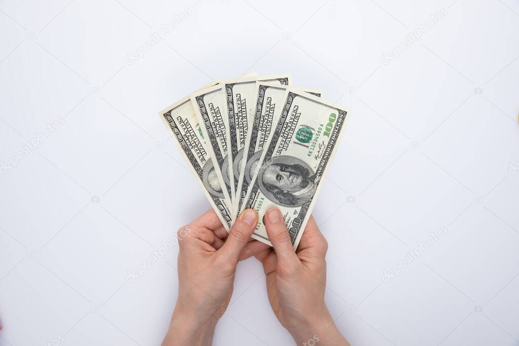 collection of hundred-dollar banknotes in female hands isolated on white background, close view