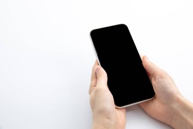 Beyaz arka planda izole edilmiş modern siyah akıllı telefonu tutan kadın elleri, yakın görüş 