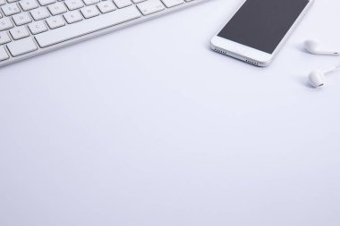 Beyaz arkaplanda izole edilmiş akıllı telefon ve kulaklıkları olan yeni modern klavye, yakın görüş 