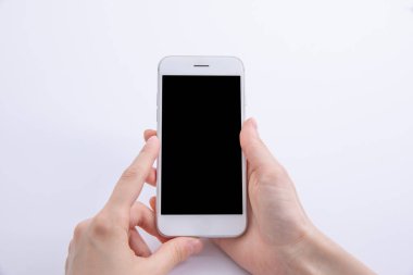 Beyaz arka planda izole edilmiş modern siyah akıllı telefonu tutan kadın elleri, yakın görüş 