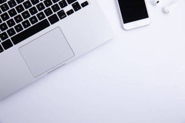 Beyaz arkaplanda izole edilmiş akıllı telefonlu yeni modern dizüstü bilgisayar ve kulaklıklar, yakın görüş 