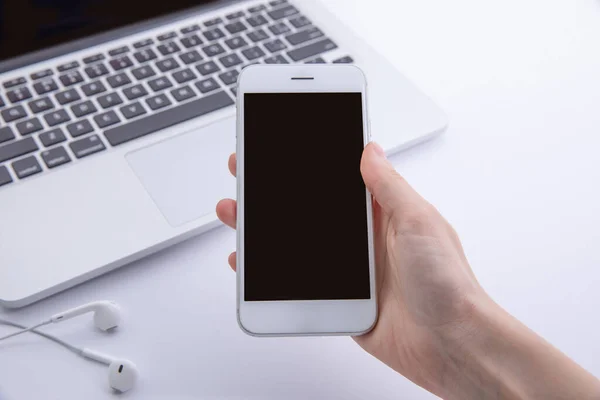 Bilgisayarlı ve kulaklıklı akıllı telefon kullanan kadın elinin üst görünümü, iş kavramı 