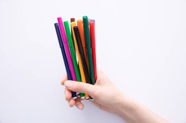 Kadın eli koyu arka planda renkli keçeli kalemler, yakın görüş. 