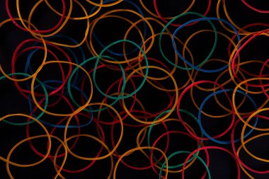 Siyah arkaplanda parlak renkli kırtasiye lastikleri, yakın görünüm  