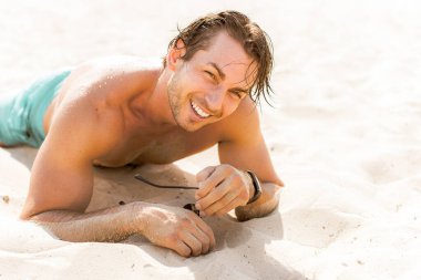 Sudaki yakışıklı adam, kaslı fit vücut gösteren seksi adam. Spor hayatı kavramı. Güneşli bir günde kumsalda kaslı bir erkek vücudu.