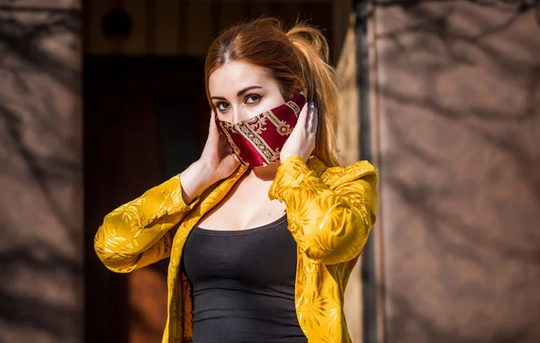 Young woman in fashionable homemade mask, scarf on her face, stop virus, save yourself