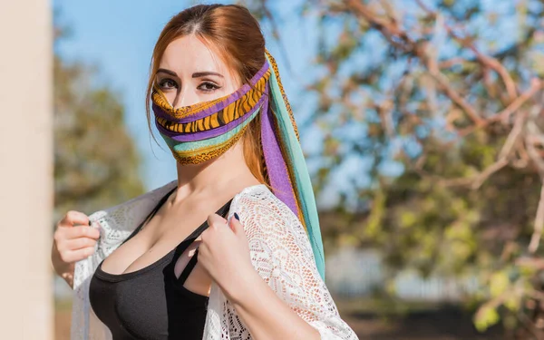 Young woman in fashionable homemade mask, scarf on her face, stop virus, save yourself