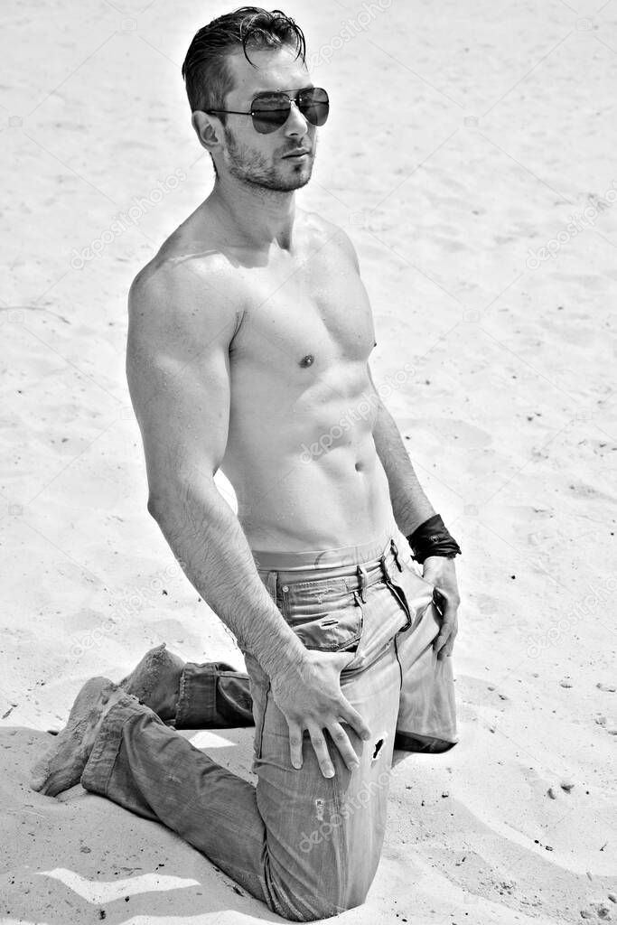 Handsome man in water, sexy guy showing muscular fit body. Concept of sport life. Muscular male bodybuilder torso on a sunny day at the beach 