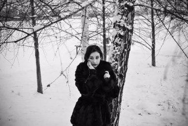 Ayrıca retro görünümlü hoş bir bayan kışın yürüyüş tarzında doğal kürk manto giymiyor. Kadının keyfi yerinde. Kış tatili, siyah beyaz fotoğraf