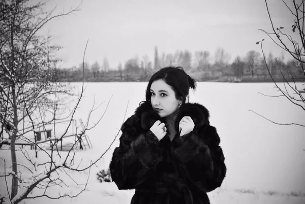 Plus size nice young lady in retro look style walk at winter time wear in not natural fur coat. Woman have a good mood. Winter holiday time, black and white photo