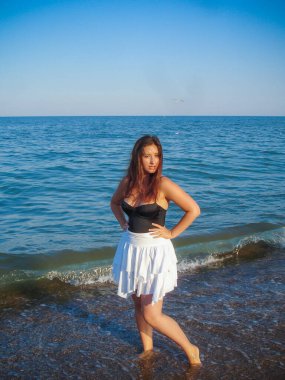 Arap genç bir kız, dolgun kalçalı, deniz kenarında dinleniyor, vücudunu gösteriyor, artı beden ölçülerinde bir kız.