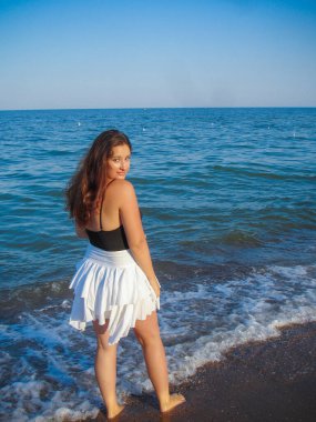 Arap genç bir kız, dolgun kalçalı, deniz kenarında dinleniyor, vücudunu gösteriyor, artı beden ölçülerinde bir kız.