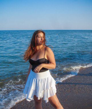 Arap genç bir kız, dolgun kalçalı, deniz kenarında dinleniyor, vücudunu gösteriyor, artı beden ölçülerinde bir kız.