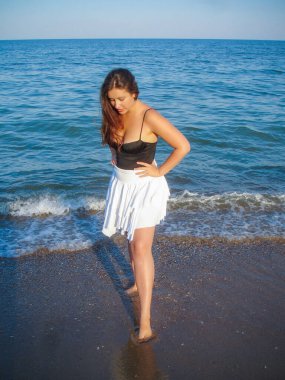 Arap genç bir kız, dolgun kalçalı, deniz kenarında dinleniyor, vücudunu gösteriyor, artı beden ölçülerinde bir kız.