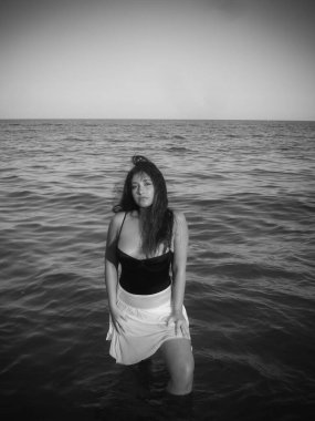 Arap genç bir kız, dolgun kalçalı, deniz kenarında dinleniyor, vücudunu gösteriyor, artı beden ölçülerinde bir kız.