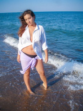 Arap genç bir kız, dolgun kalçalı, deniz kenarında dinleniyor, vücudunu gösteriyor, artı beden ölçülerinde bir kız.