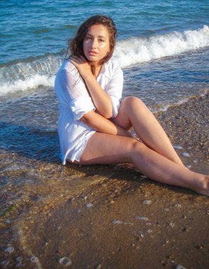 Arap genç bir kız, dolgun kalçalı, deniz kenarında dinleniyor, vücudunu gösteriyor, artı beden ölçülerinde bir kız.