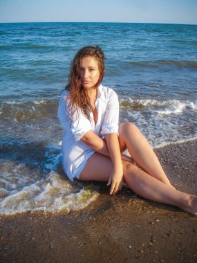 Arap genç bir kız, dolgun kalçalı, deniz kenarında dinleniyor, vücudunu gösteriyor, artı beden ölçülerinde bir kız.