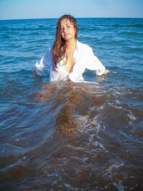 Arap genç bir kız, dolgun kalçalı, deniz kenarında dinleniyor, vücudunu gösteriyor, artı beden ölçülerinde bir kız.