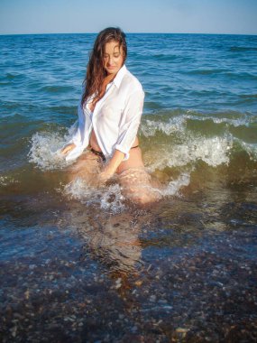 Arap genç bir kız, dolgun kalçalı, deniz kenarında dinleniyor, vücudunu gösteriyor, artı beden ölçülerinde bir kız.