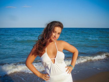 Arap genç bir kız, dolgun kalçalı, deniz kenarında dinleniyor, vücudunu gösteriyor, artı beden ölçülerinde bir kız.