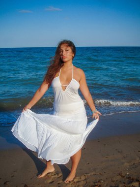 Arap genç bir kız, dolgun kalçalı, deniz kenarında dinleniyor, vücudunu gösteriyor, artı beden ölçülerinde bir kız.