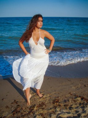 Arap genç bir kız, dolgun kalçalı, deniz kenarında dinleniyor, vücudunu gösteriyor, artı beden ölçülerinde bir kız.