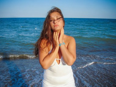 Arap genç bir kız, dolgun kalçalı, deniz kenarında dinleniyor, vücudunu gösteriyor, artı beden ölçülerinde bir kız.