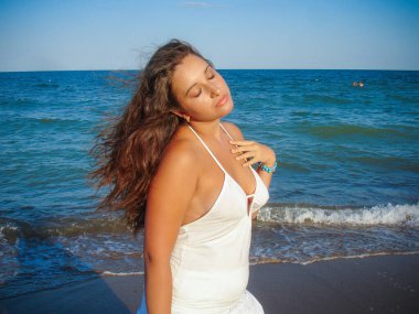 Arap genç bir kız, dolgun kalçalı, deniz kenarında dinleniyor, vücudunu gösteriyor, artı beden ölçülerinde bir kız.