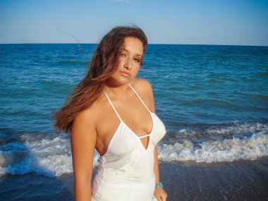 Arap genç bir kız, dolgun kalçalı, deniz kenarında dinleniyor, vücudunu gösteriyor, artı beden ölçülerinde bir kız.