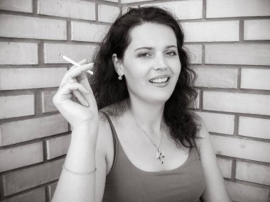 Nikotinin kadın sağlığı ve görünüşü üzerindeki zararlı etkisi. Sigara içen orta yaşlı bir kadın balkonda oturup sigara içiyor. Zararlı alışkanlıklardan zarar görür