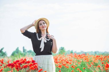 Gelincik tarlasında eski püskü bluz ve dantelli etek giyen kızıl saçlı kadın. Kadınlar için şık bir tarz.