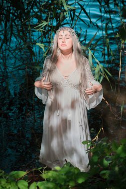 Gölde beyaz elbiseli deniz kızı gelini. Fantezi kızı. Gizemli bir sahne. Cadı nehirde duruyor ve büyü yapıyor. Peri masalı