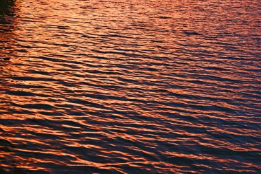 Gün batımında sakin suda küçük dalgalar 