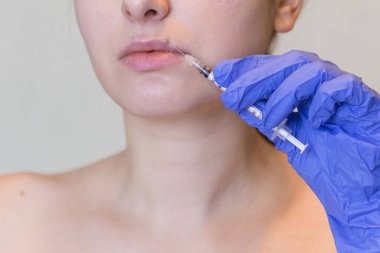 Genç bir kadının doğal görünüşü kozmetik enjeksiyon yaptırır. Doktorların elleri yüzünden iğne yapıyor. Güzellik Tedavisi