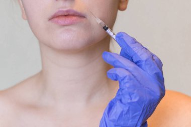 Genç bir kadının doğal görünüşü kozmetik enjeksiyon yaptırır. Doktorların elleri yüzünden iğne yapıyor. Güzellik Tedavisi