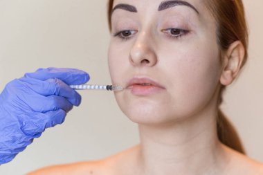 Genç bir kadının doğal görünüşü kozmetik enjeksiyon yaptırır. Doktorların elleri yüzünden iğne yapıyor. Güzellik Tedavisi