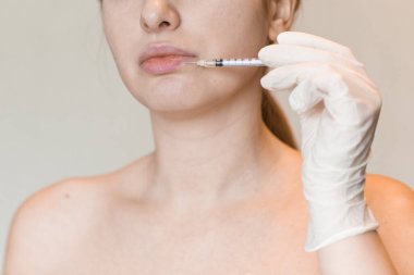 Genç bir kadının doğal görünüşü kozmetik enjeksiyon yaptırır. Doktorların elleri yüzünden iğne yapıyor. Güzellik Tedavisi