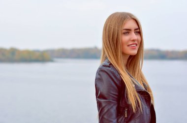 Uzun sarı saçlı, modaya uygun, modern bir kadın sokakta takılıyor. Süslü poz veren güzel bayan 