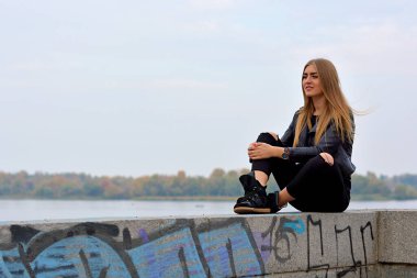 Uzun sarı saçlı, modaya uygun, modern bir kadın sokakta takılıyor. Süslü poz veren güzel bayan 