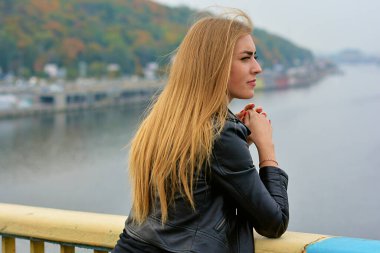 Uzun sarı saçlı, modaya uygun, modern bir kadın sokakta takılıyor. Süslü poz veren güzel bayan 