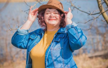 Olgun bir kadın, Amerikan ya da Avrupa 'da yürüyüş ve hayatın tadını çıkarmak. Kilolu bir kadın, şehir parkında şık giyinmiş. Doğal güzellik.