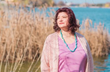 Olgun bir kadın, Amerikan ya da Avrupa 'da yürüyüş ve hayatın tadını çıkarmak. Kilolu bir kadın, şehir parkında şık giyinmiş. Doğal güzellik.