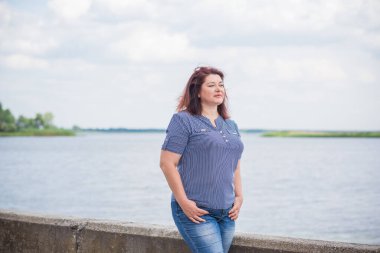 Olgun bir kadın, Amerikan ya da Avrupa 'da yürüyüş ve hayatın tadını çıkarmak. Kilolu bir kadın, şehir parkında şık giyinmiş. Doğal güzellik.