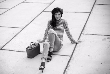 Modern Fransız tarzı genç bir kadın, kot pantolon ve jemper giyiyor, şapka takıyor. Günlük yaşam için günlük moda tarzı